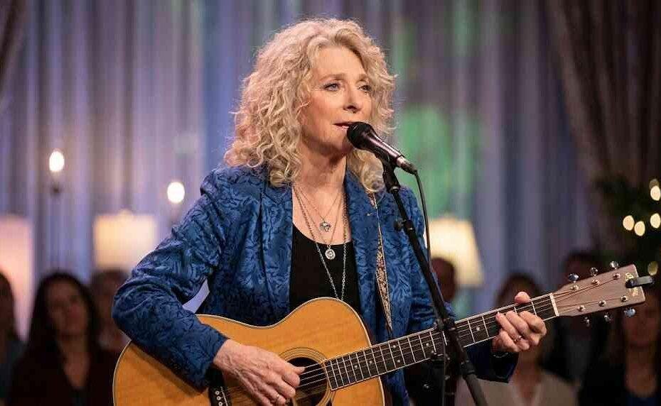 Judy Collins performing live on stage with an acoustic guitar and microphone